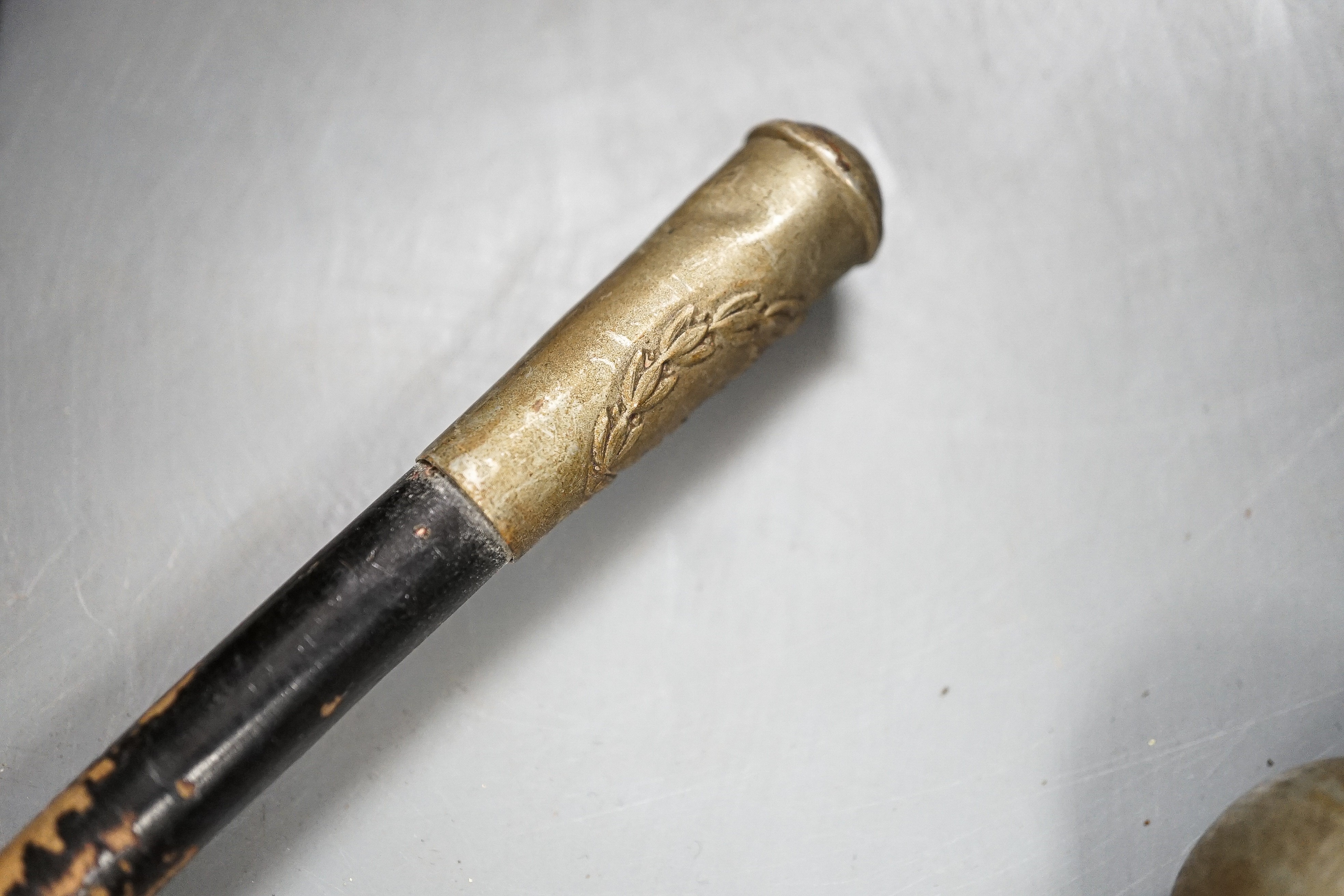 A group of WWI and WWII militaria badges, buttons, two swagger sticks, an armband and a World War I German POW inscribed plaster ornament, longest swagger stick 70 cms long.